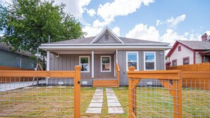 A residential house with a grey exterior, a front porch, and a fenced yard. - Seize the Moment! 4br/3ba Gem w/ Downtown Views! (San Antonio)