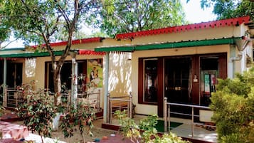 A building with a red and white facade, a covered entrance, and potted plants in the foreground.