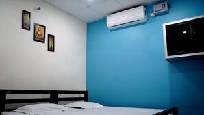 Una habitación con una cama, aire acondicionado de pared y tres cuadros enmarcados.