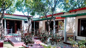 Un patio con piso de baldosas, plantas en macetas y una pequeña fuente.