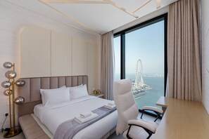 Een hotelkamer met een bed, een bureau, een stoel en uitzicht op een reuzenrad.