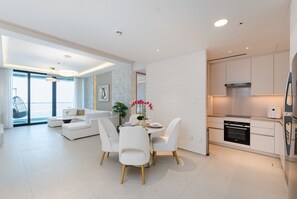 A modern living room with a dining area, a kitchen, and a large window with a view.