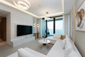Un salon moderne doté d’un grand téléviseur à écran plat, de canapés blancs, d’une cheminée en marbre et d’un balcon offrant une vue imprenable.