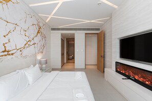Une chambre d’hôtel moderne dotée d’un grand lit, d’une télévision à écran plat et d’une cheminée intégrée.