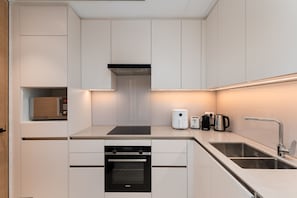 A modern kitchen with white cabinetry, a built-in oven, a coffee maker, and a toaster. - Address JBR Elegant 2BR w/ Beach Access (Dubai)