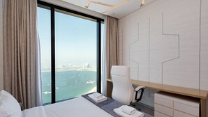 Ein modernes Hotelzimmer mit einem großen Bett, einem Schreibtisch und Blick auf eine Stadtlandschaft und Wasser.