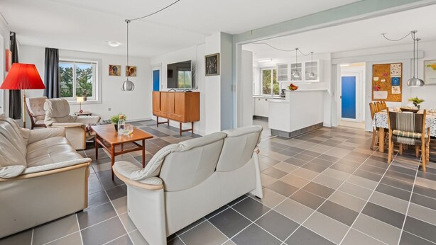 Una sala moderna con sofá, mesa de comedor y zona de cocina con puerta azul.