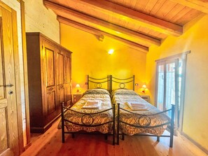 Quarto com duas camas, guarda-roupa de madeira e janela com cortinas.