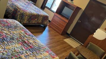A hotel room with two beds, a TV, a desk, and a chair.