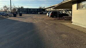 A parking lot with several cars and a building with a covered area.