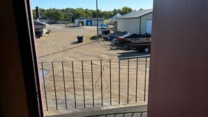 A view from inside a building looking out to a parking area with a number 234 sign, a fenced area, and some buildings in the background.