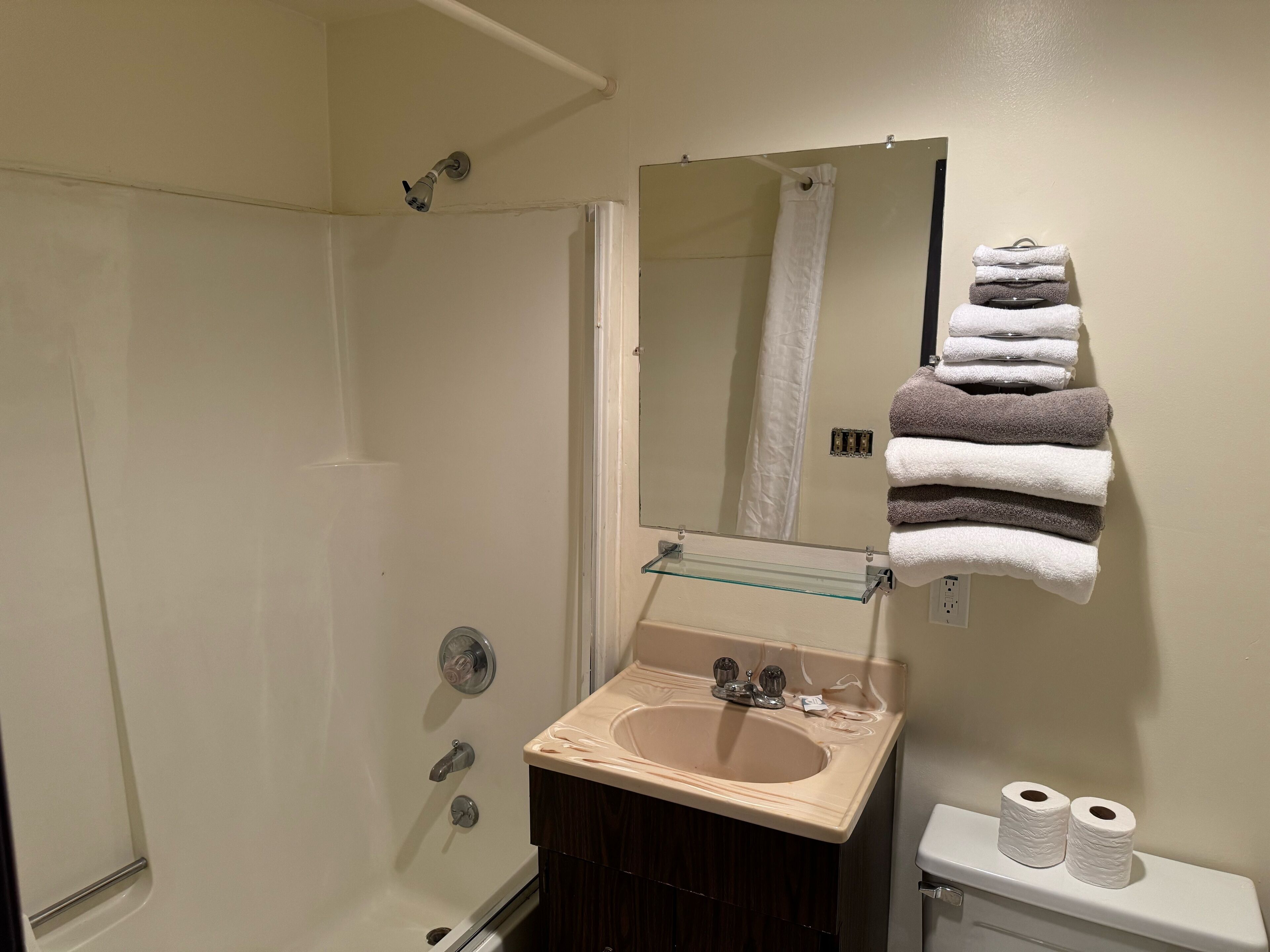 Ein Badezimmer mit Waschbecken, Spiegel, Handtuchhalter, Toilette und Dusche.