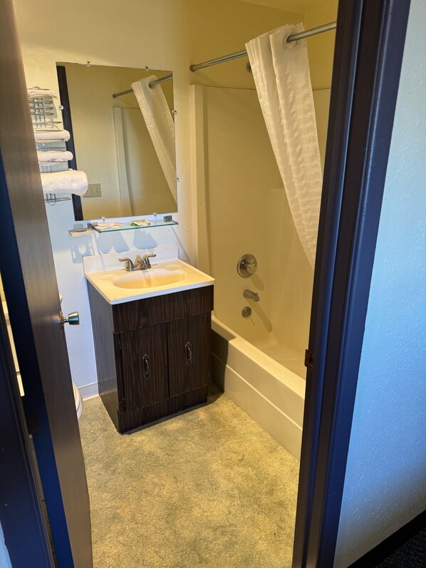 A bathroom with a sink, dark wooden cabinets, a glass shower enclosure, and a towel rack with towels.