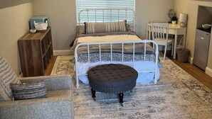 A bedroom with a sloped ceiling, a bed with a white frame, a small round table, a chair, a desk, a ceiling fan, and a window with blinds. - Charming studio with WiFi, AC and a pool in fabulous Oakdale (Oakdale)
