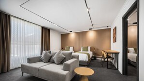 A modern hotel room with a sofa, a bed, a small table, and a dining area. - Innova Motel Warrnambool (Warrnambool)