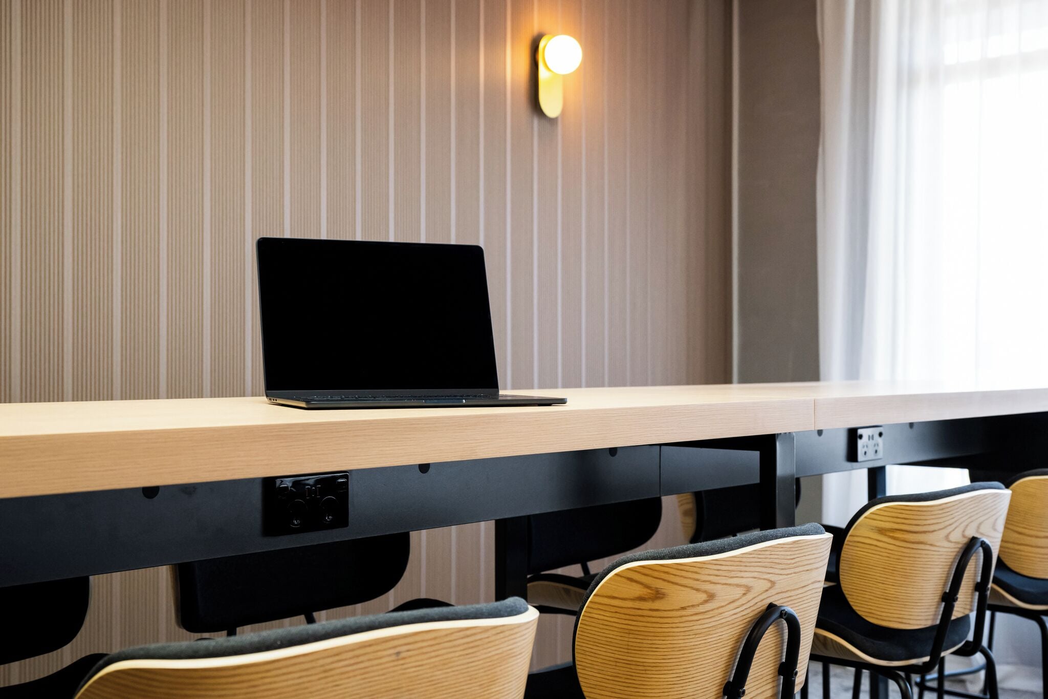 Una sala de conferencias con una larga mesa, una computadora portátil y varias sillas.