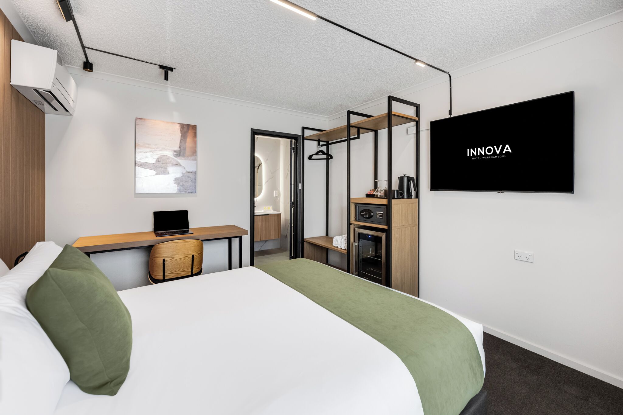 Una habitación de hotel moderna con cama, escritorio, televisión y kitchenette.