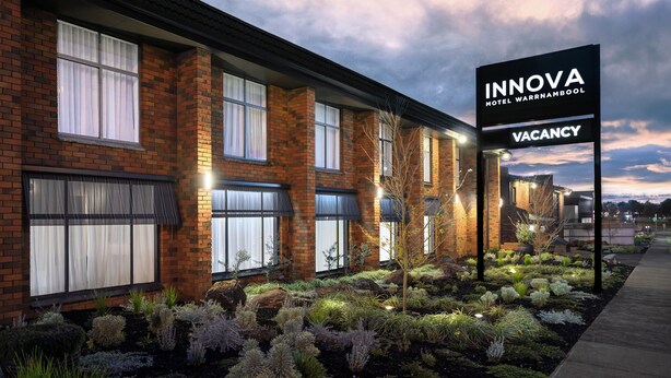A hotel with a brick facade, large windows, and a sign indicating vacancy. - Innova Motel Warrnambool (Warrnambool)