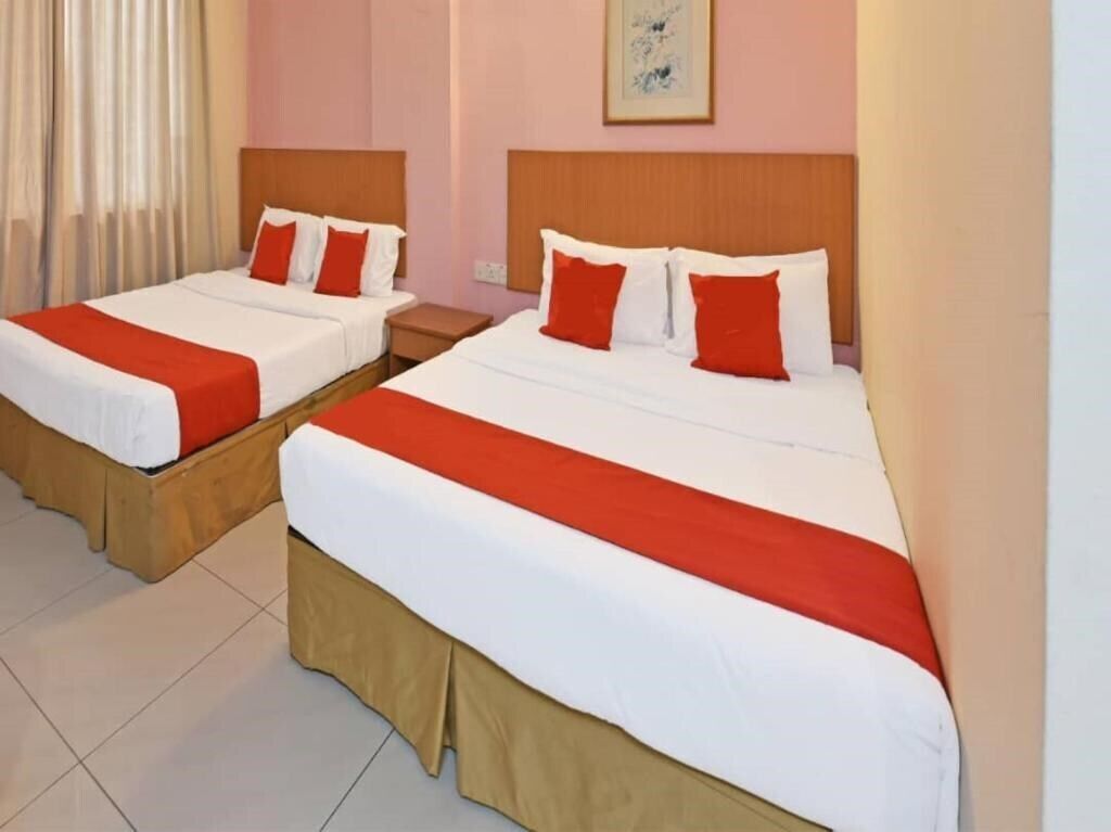 Two double beds with red and white bedding, wooden headboards, and a beige skirtboard.