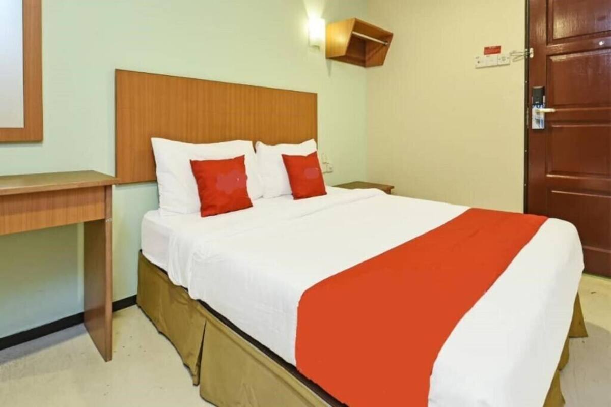 A hotel room with a bed, a wooden headboard, a nightstand, and a door.