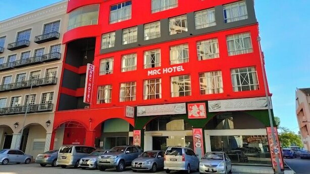 Un hôtel à plusieurs étages, avec une façade rouge et des balcons.