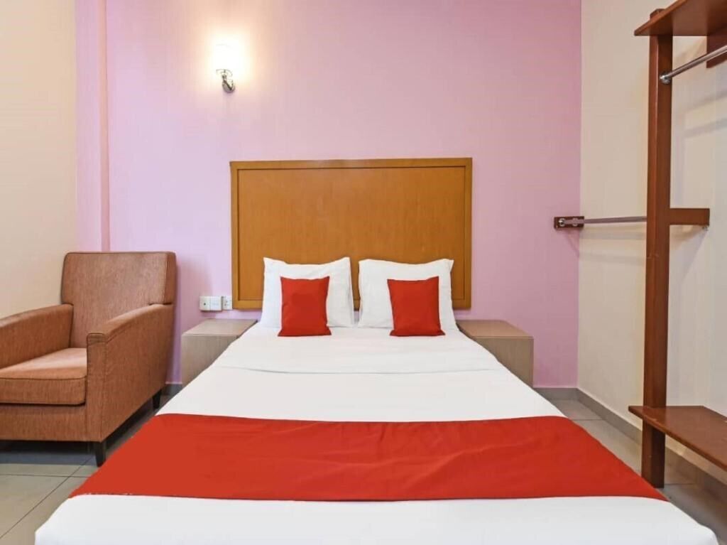 A hotel room with a bed, a chair, a nightstand, and a wooden headboard.