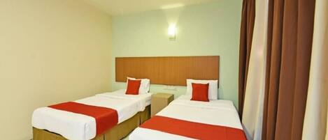 A hotel room with two beds, each with a wooden headboard, white bedding, and red accents.