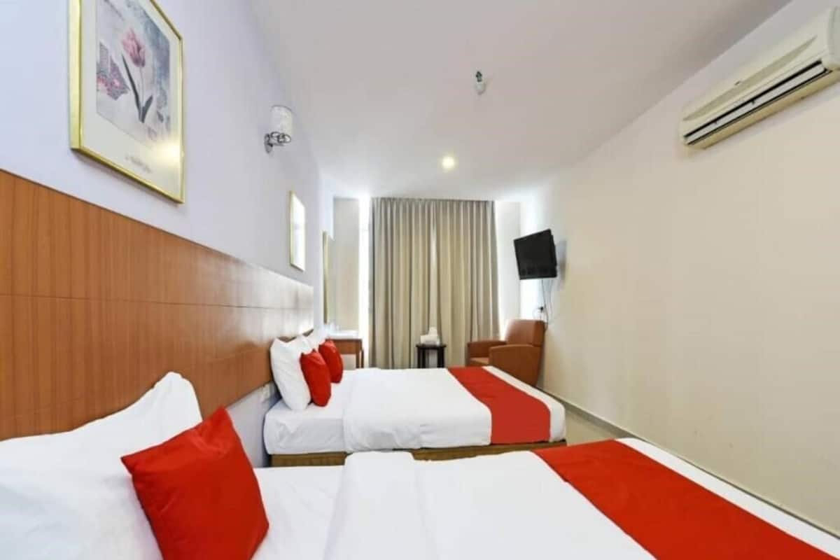 A hotel room with two beds, a wooden headboard, a flat-screen TV, and an air conditioning unit.