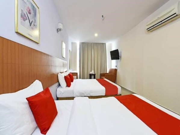 A hotel room with two beds, a wooden headboard, a flat-screen TV, and an air conditioning unit.