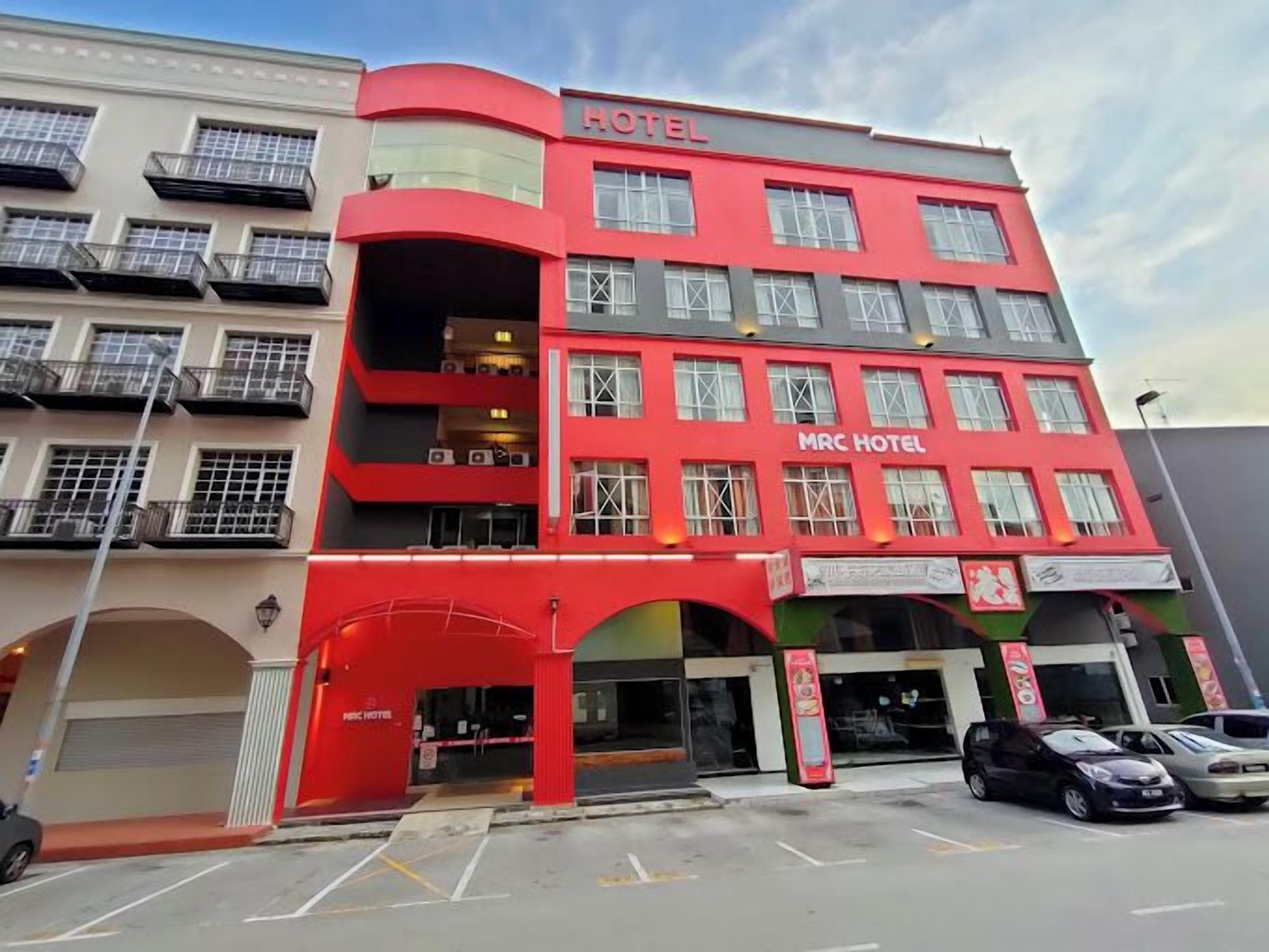 Ein mehrstöckiges Hotel mit Balkonen und einer roten Fassade.