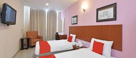 A hotel room with two beds, a television, a chair, and a desk with a lamp.
