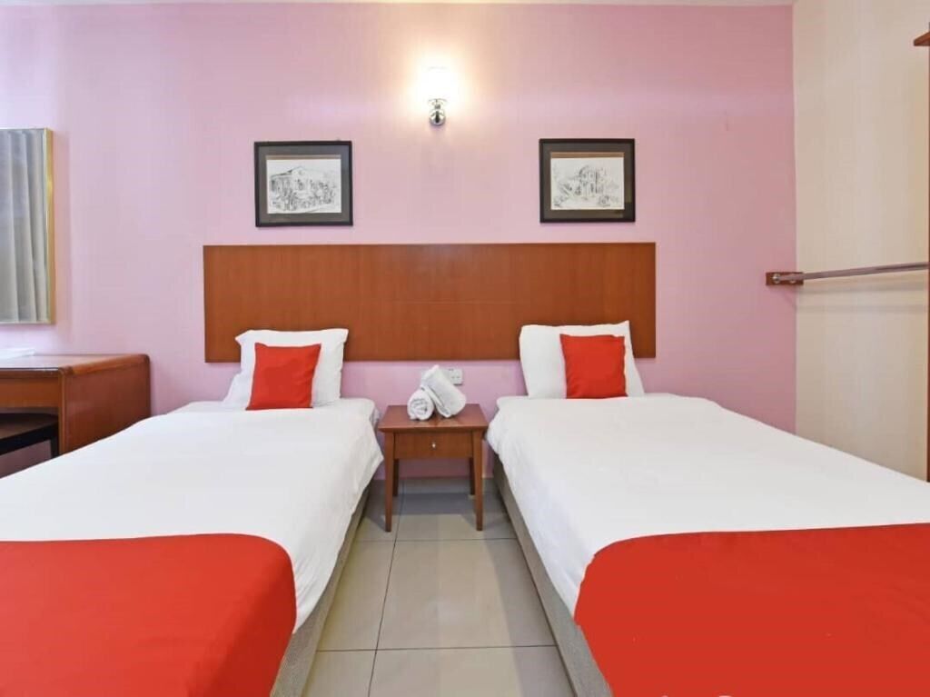 Une chambre d’hôtel avec deux lits, une tête de lit en bois et une table de chevet avec une lampe.