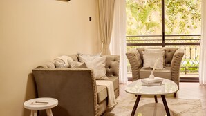 A living room with a beige sofa, a matching armchair, and a small round table. - Sand Grains Residences 001 (Entebbe)