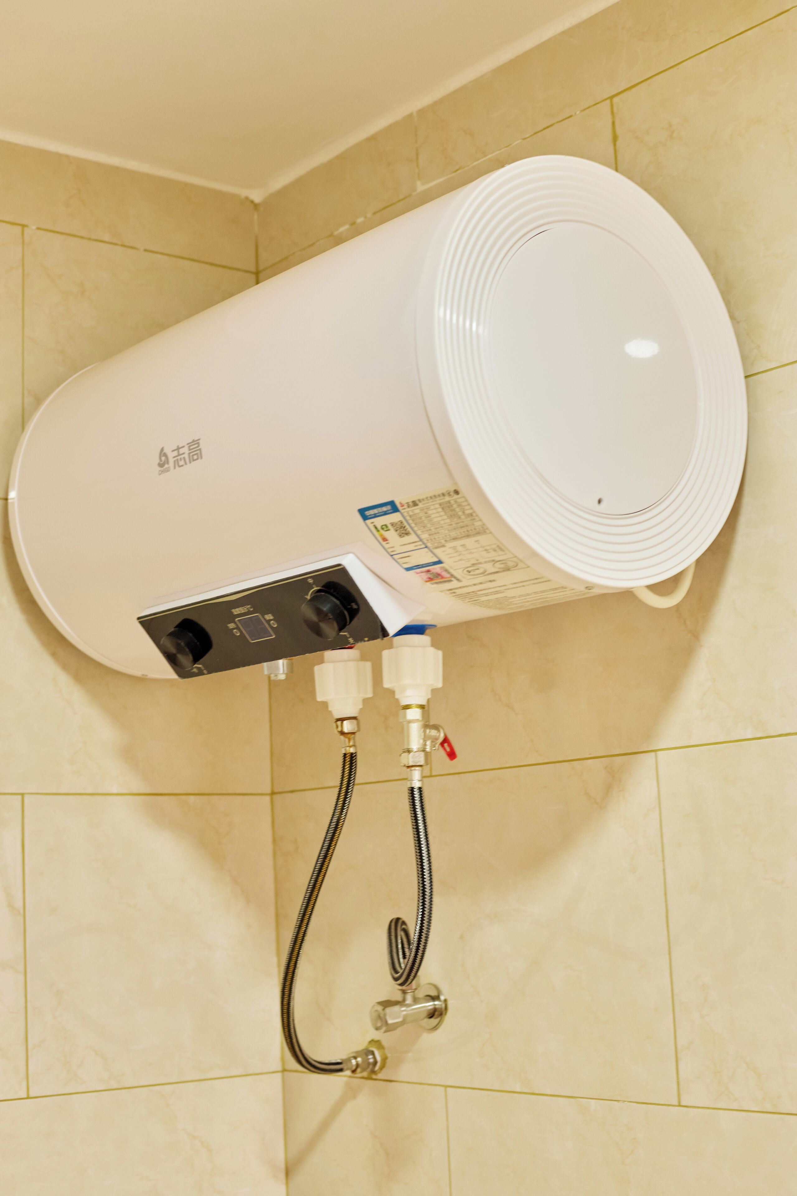 A wall-mounted water heater with control panel and hoses.