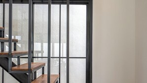 Een moderne trap met houten treden en metalen leuningen, die leidt naar een kamer met een groot raam.