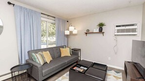 A modern living room with a grey sofa, a coffee table, a TV, and a small side table.