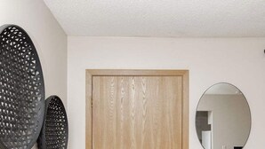 A wooden door with a simple design, a round mirror on the wall, and a decorative rug with a fan-like pattern.