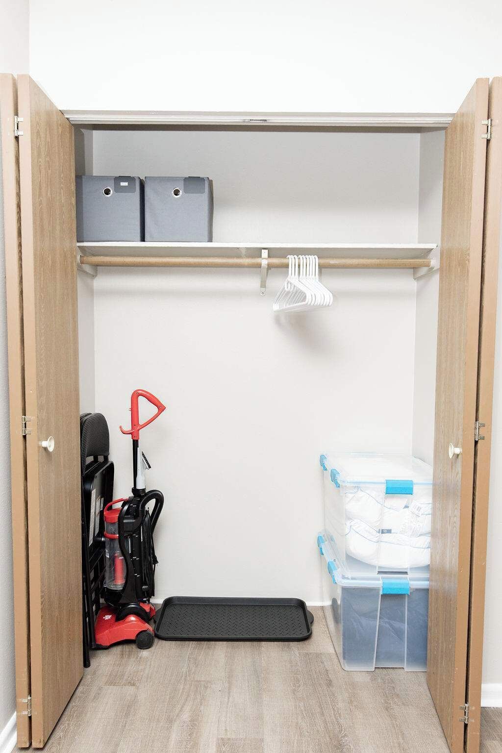 Un depósito de almacenamiento compacto con estantes, un aspirador y recipientes de plástico.