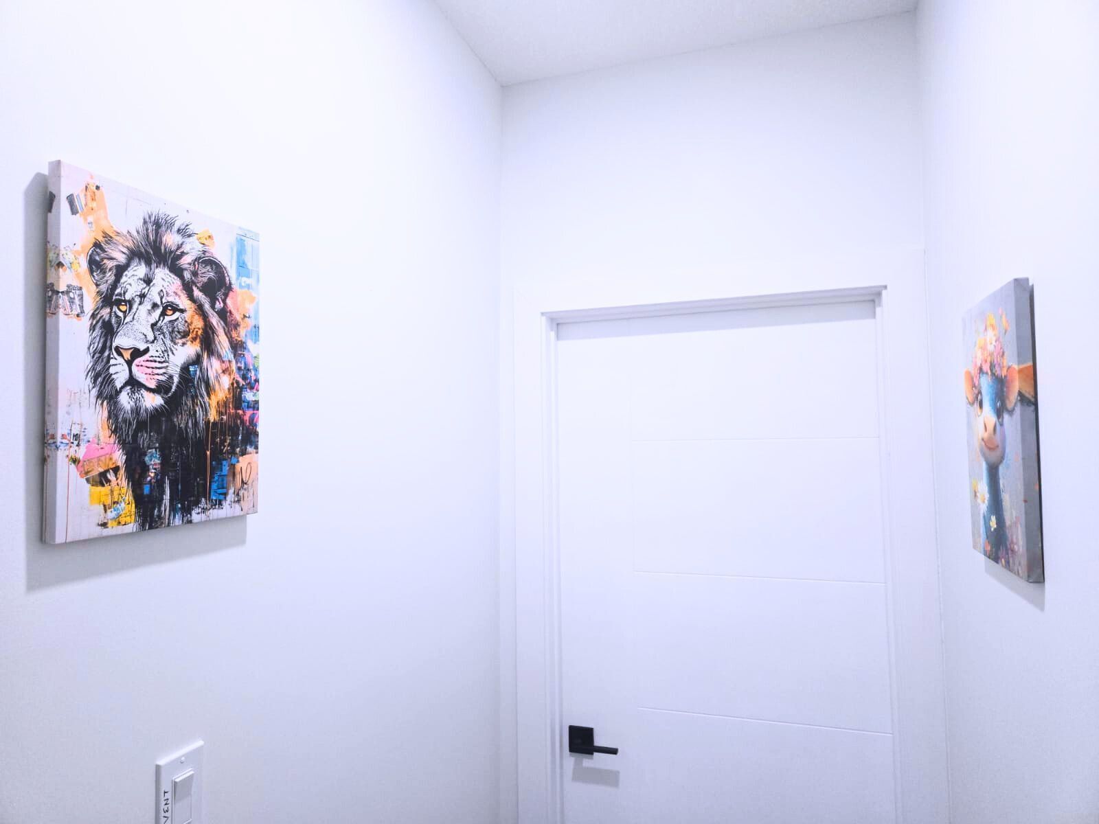 Une pièce aux murs blancs, une porte fermée et deux œuvres d’art accrochées aux murs.