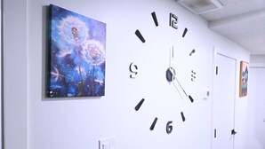 A hallway with a large wall clock, a painting of dandelions, and a door. - St. Albert Luxury New 2BR/2BA Basement • Private Entrance • Pet-Friendly (St. Albert)