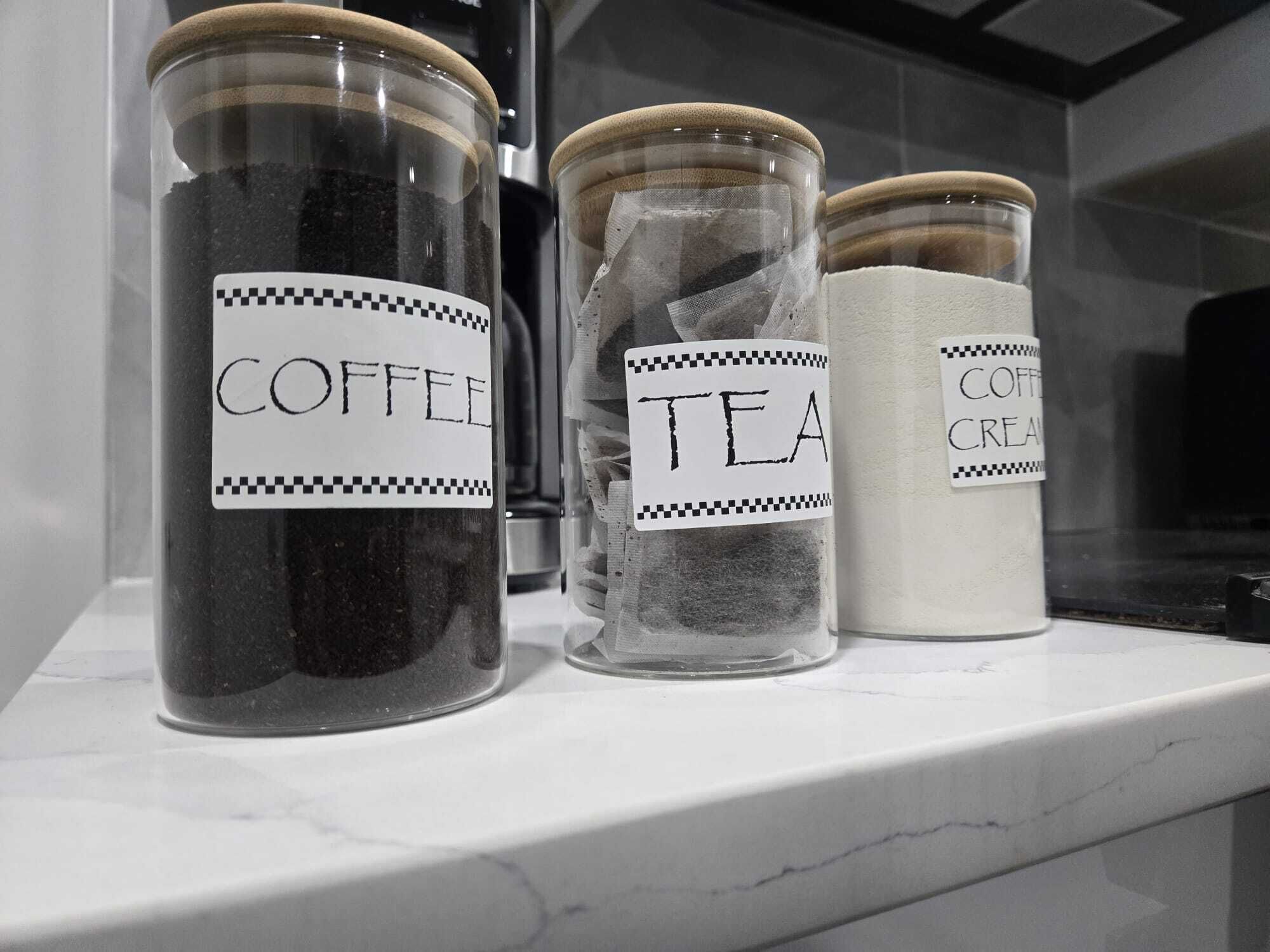 Trois bocaux en verre, étiquetés, posés sur un comptoir en marbre blanc.