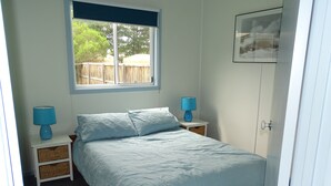 Une chambre à coucher avec un lit, deux tables de chevet, une fenêtre et une porte.