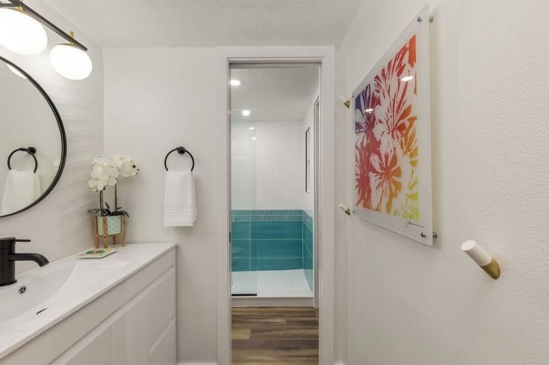 Un baño con un lavabo blanco, un espejo y una ducha con azulejos azules.