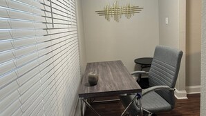 A small meeting room with a table, a chair, a decorative wall piece, and a window with blinds. - I042 – Upgraded 2BD Apt | Pool | DFW South 183/161 (Irving)