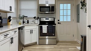 Una cocina moderna con armarios blancos, un microondas de acero inoxidable y un horno.