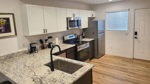 Una cocina moderna con armarios blancos, electrodomésticos de acero inoxidable y encimera de granito.