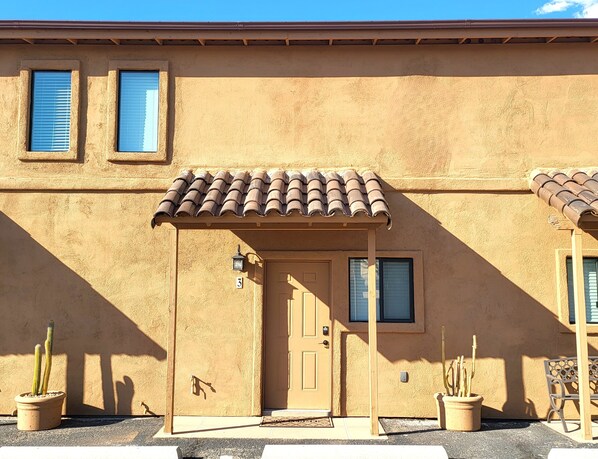 A building with a beige stucco exterior, a tiled roof, and a door with a number '3' sign. There are two potted cacti and a bench to the right. - "Two-Story Townhome Newly Renovated One-Bedroom Getaway Awaits Your Stay!" (Tucson)