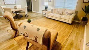 A living room with a ceiling fan, a sofa, a dining table with chairs, and a coffee table. - EastGate 4A Cozy family retreat close to downtown Hammond (Hammond)