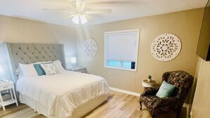 A bedroom with a bed, a nightstand, a chair, and a ceiling fan. - EastGate 4A Cozy family retreat close to downtown Hammond (Hammond)