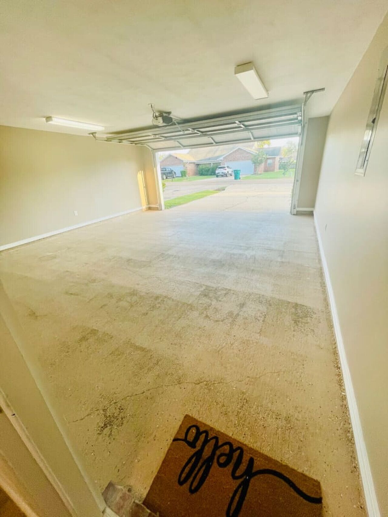 A garage with a concrete floor and a doormat with the word "welcome" on it.